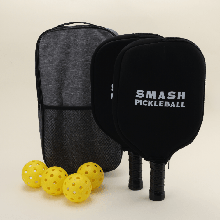 A pickleball set featuring four yellow hybrid pickleballs, two paddles with black covers, and a carrying bag, arranged neatly on a surface.
