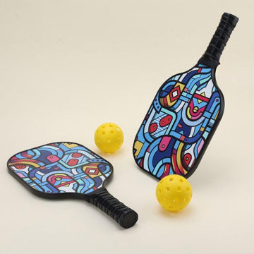 A pickleball set featuring two paddles with modern, artistic patterns in bold, vibrant colors, four yellow pickleballs, and a black pickleball carry bag, arranged to showcase the unique and stylish design.