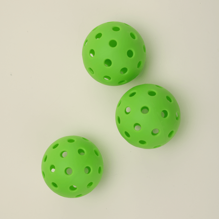 Ceiling view of three green hybrid pickleballs arranged one behind another, highlighting their vibrant color and durable design.