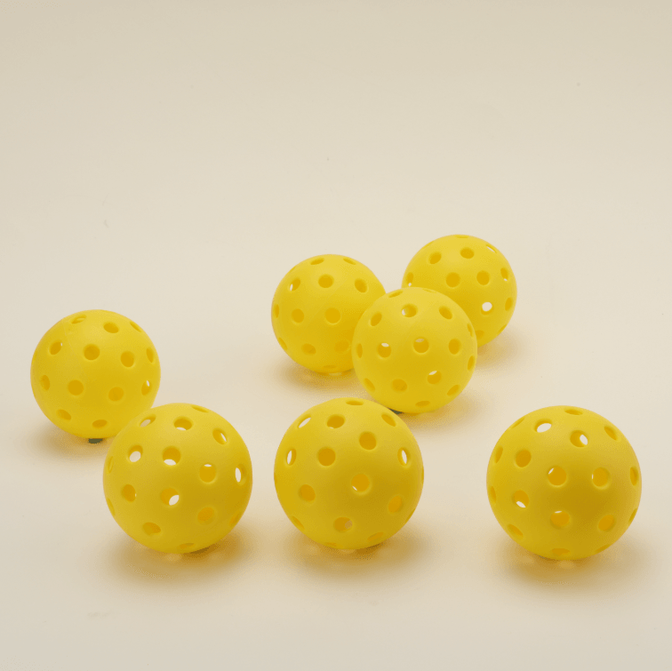 Front view of 7 pieces of yellow hybrid pickleball side by side.