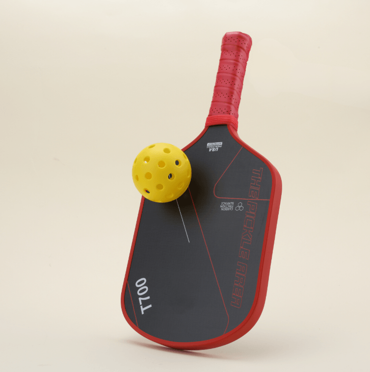 Front view of the T700 Carbon Fiber pickleball paddle in red-and-black, featuring geometric line patterns, with a yellow pickleball resting on the paddle, showcasing a dynamic and stylish design perfect for performance-driven players.