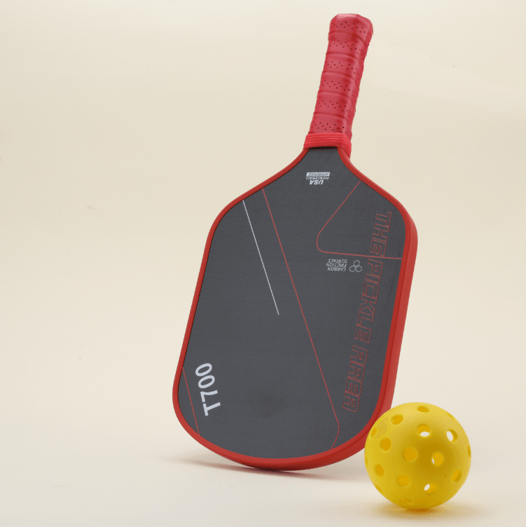 Left-side view of the T700 Carbon Fiber pickleball paddle in red-and-black, with a yellow pickleball placed next to it, showcasing a modern, geometric design perfect for both style and performance.