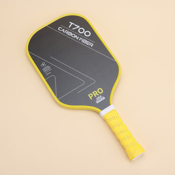 Close-up of the T700 carbon fiber pickleball paddle featuring a sleek black surface with yellow accents and ergonomic grip for enhanced performance. Ideal for both competitive players and enthusiasts.