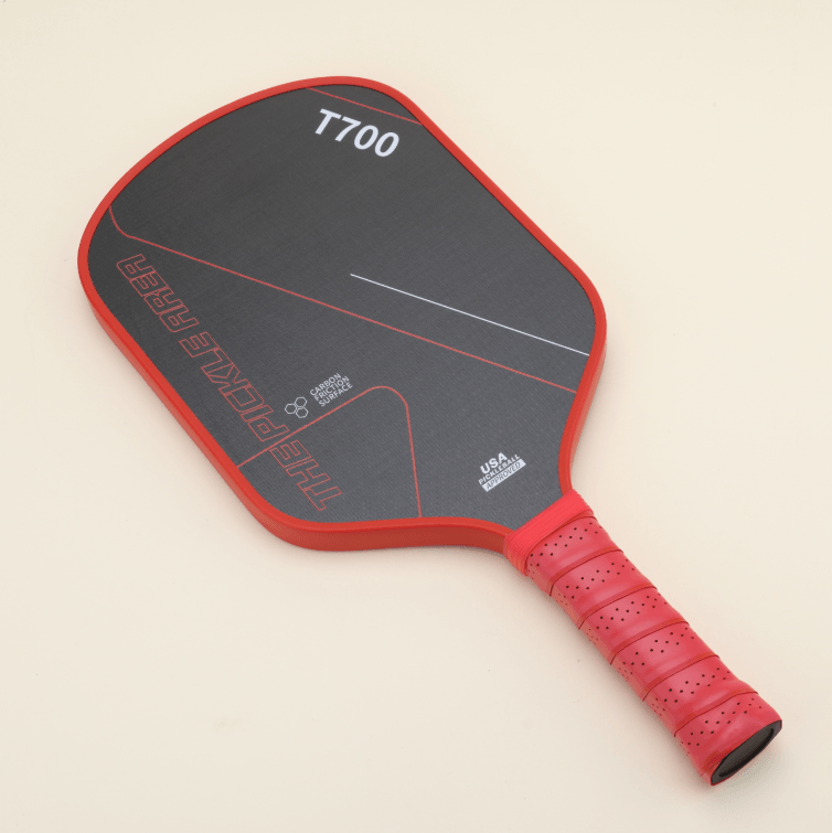 T700 Carbon Fiber pickleball paddle laid flat, featuring a bold red-and-black color scheme with geometric line patterns.