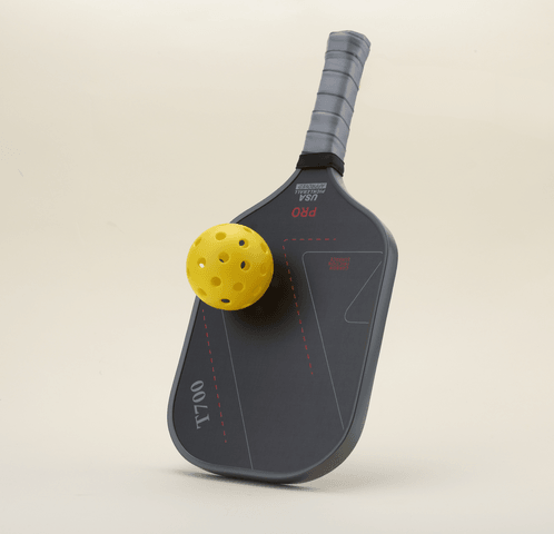 T700 Carbon Fiber pickleball paddle viewed from the left angle, featuring a sleek black-and-gray color scheme with geometric line patterns, offering a professional and stylish look. The paddle is paired with 1 yellow pickleball resting on it .