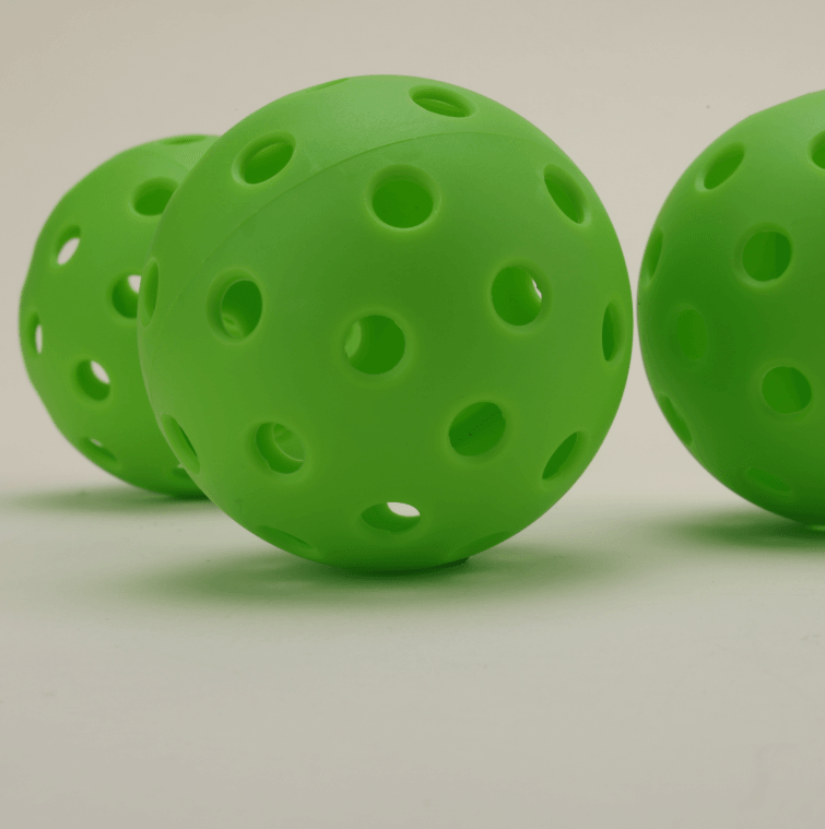 Three green hybrid pickleballs arranged together, highlighting their vibrant color and durable design.