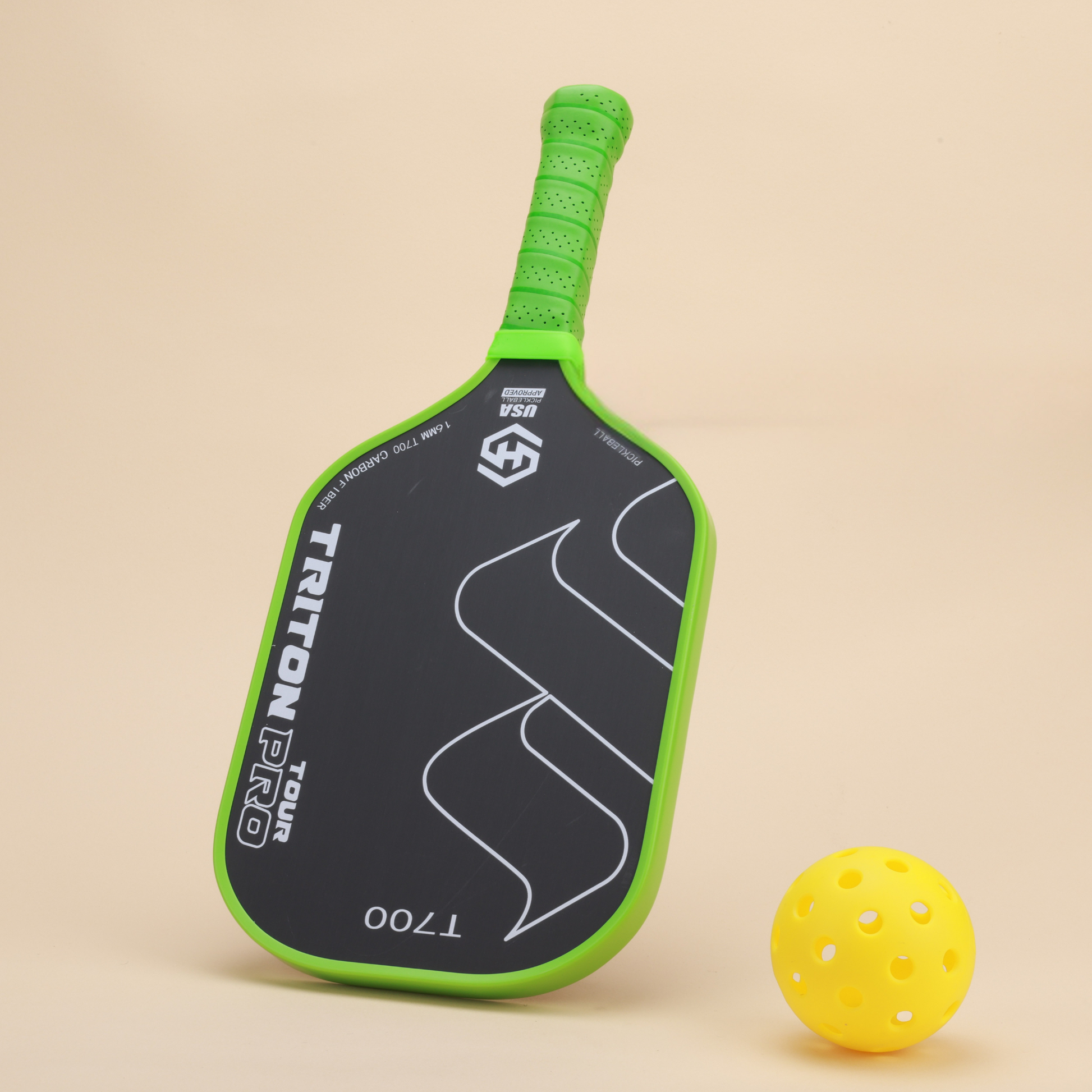 "Close-up of Triton Pro T700 pickleball paddle with a yellow pickleball beside it. The paddle features a green performance grip and carbon fiber face for improved durability and control during play."

