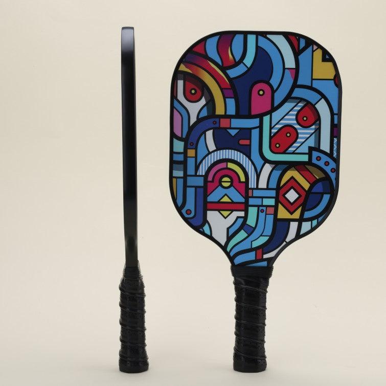 Two pickleball paddles with modern, artistic patterns in bold, vibrant colors—one shown from the front view and the other from the side, emphasizing the unique style and dynamic design of the gear.