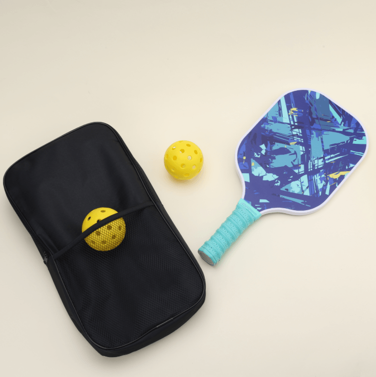 Two yellow hybrid pickleballs, one placed in the outer net compartment of a black bag, with a paddle featuring a unique blue abstract pattern, full of modern flair and energy, laying flat. The vibrant design of the paddle makes your gear stand out and express your unique style.