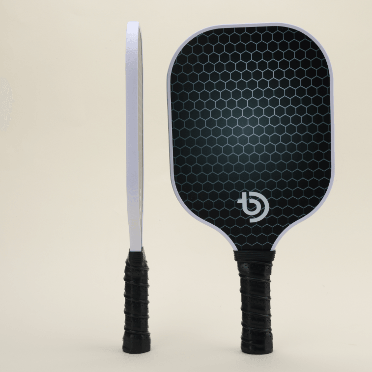 USA-approved pickleball set with 2 paddles, showcasing one paddle in side view and the other in front view. Both paddles feature a minimalistic design with a classic mesh pattern and black finish. The set also includes 4 yellow pickleballs, 2 black Smash Pickleball branded paddle covers, and 1 black carry bag, ideal for recreational and competitive play.