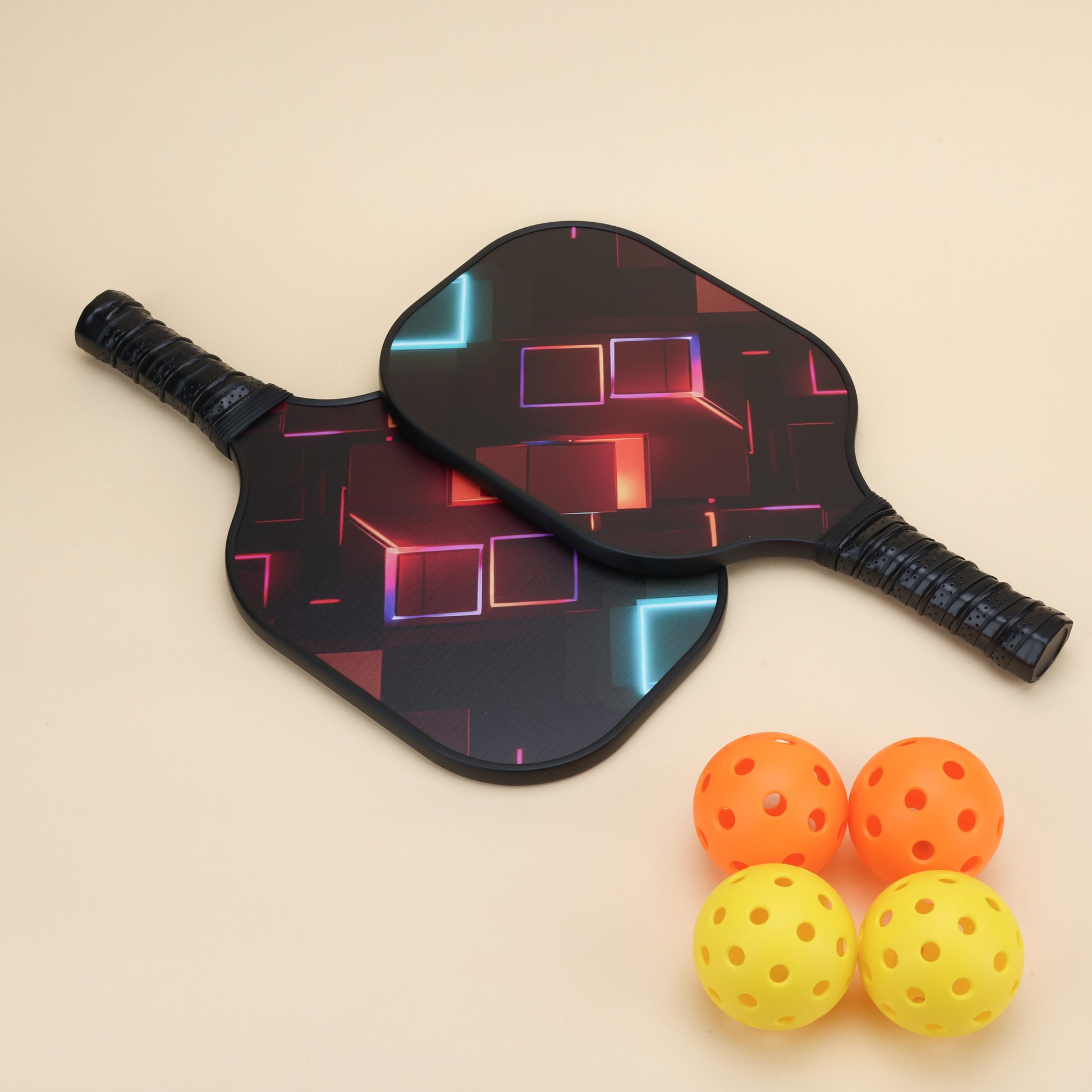 "Two high-quality pickleball paddles with a sleek geometric design, accompanied by four colorful pickleball balls in orange and yellow. Perfect for players seeking a stylish and performance-focused pickleball set."
